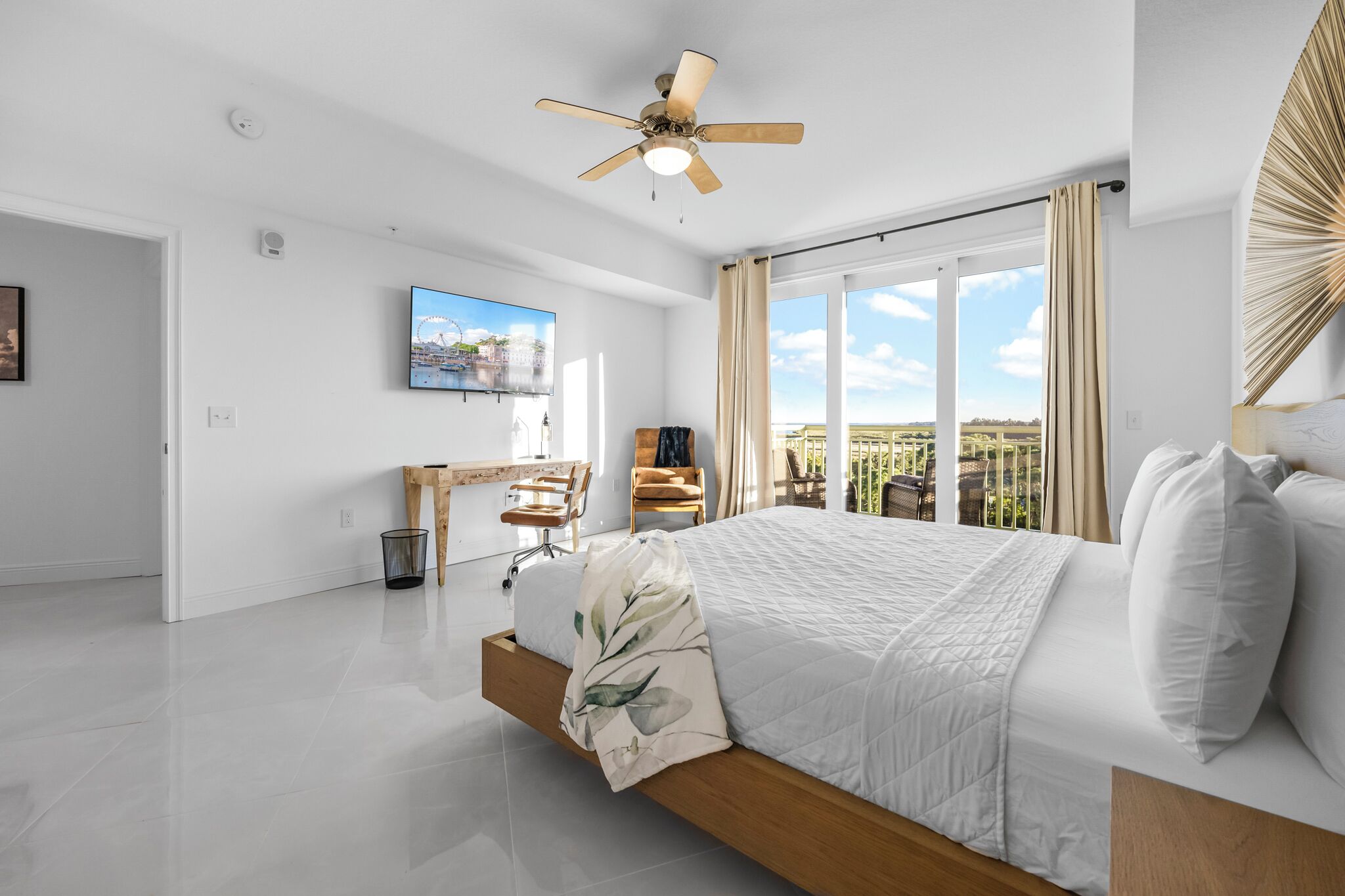 A modern bedroom with a large bed, a desk, and a chair.