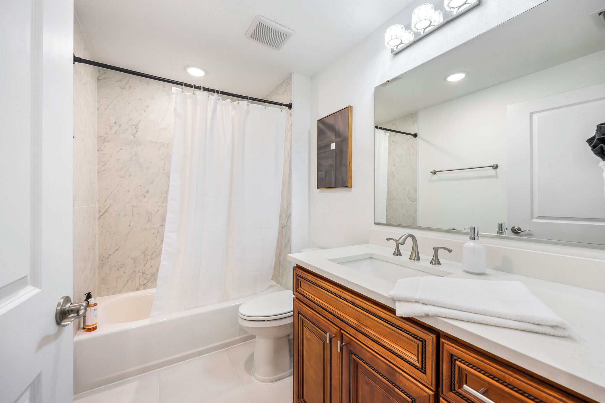 A modern bathroom with a bathtub, toilet, and vanity with a mirror.