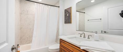A modern bathroom with a bathtub, toilet, and vanity with a mirror.