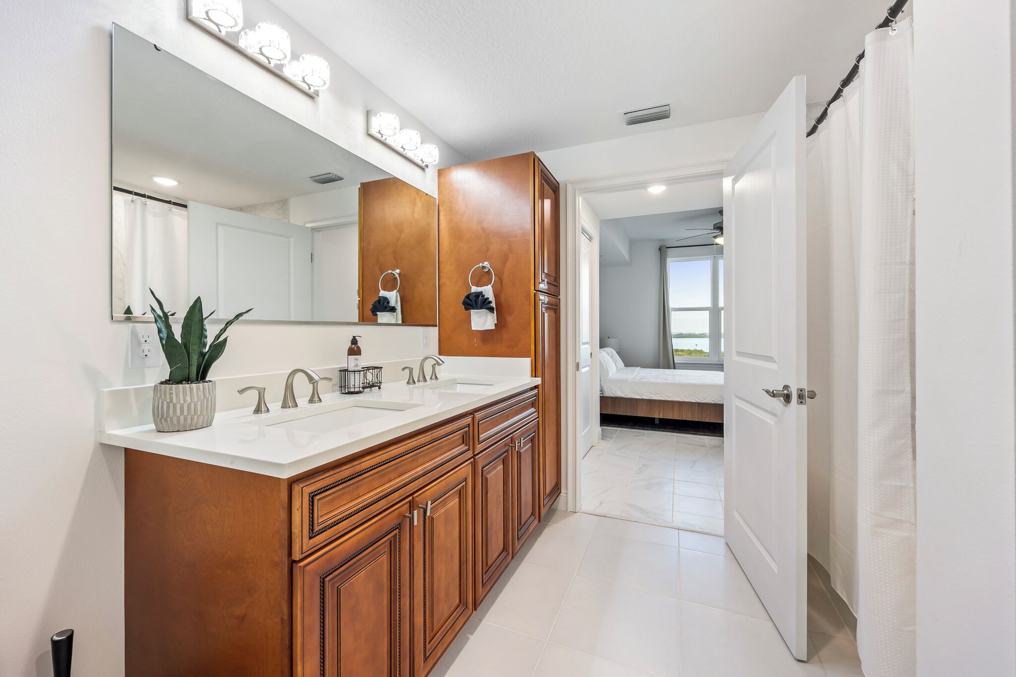 A modern bathroom with a large mirror, dual sinks, and wooden cabinetry.