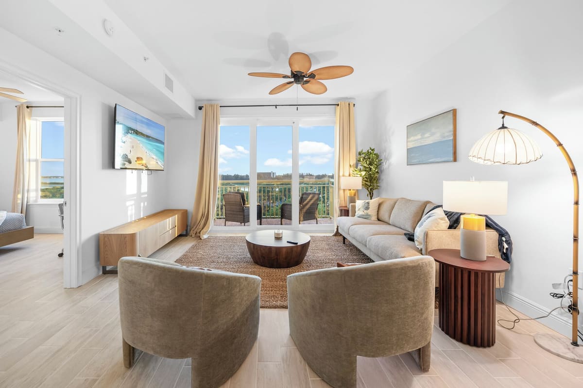 A modern living room with a sofa, two armchairs, a coffee table, and a ceiling fan.