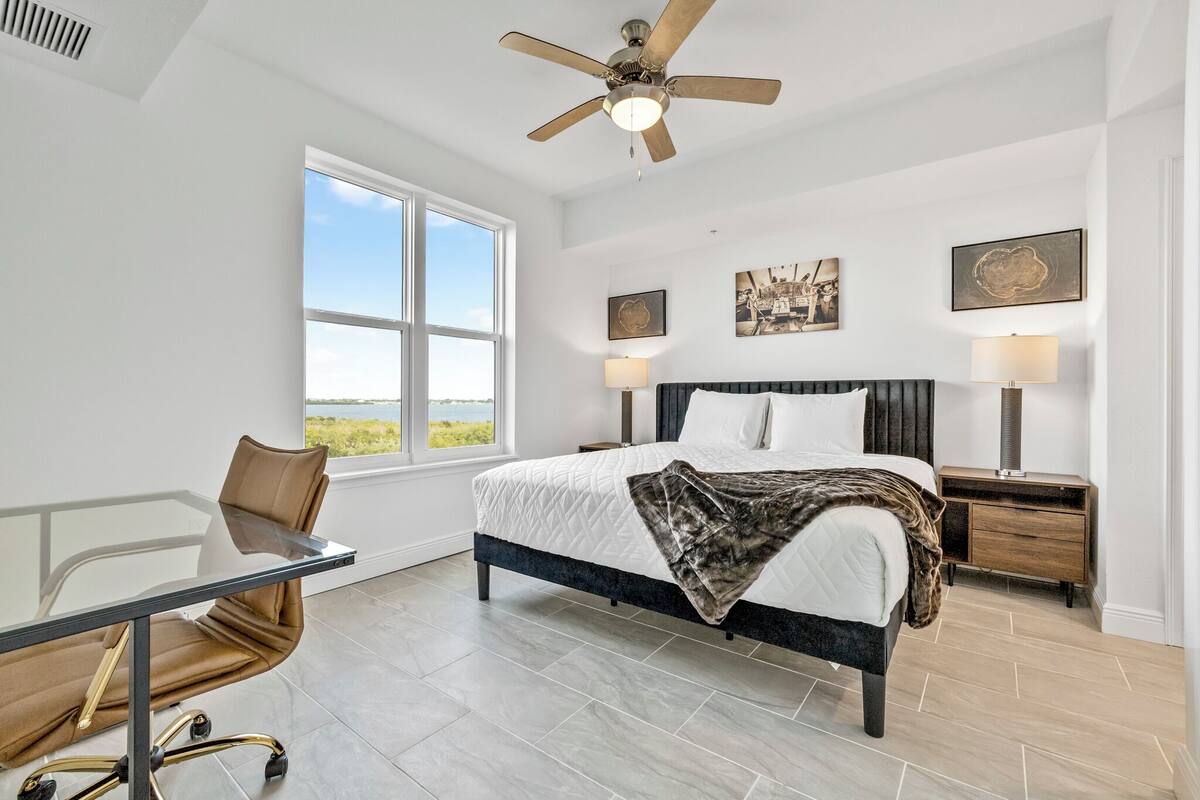 A bedroom with a bed, bedside tables, a desk, and a chair.