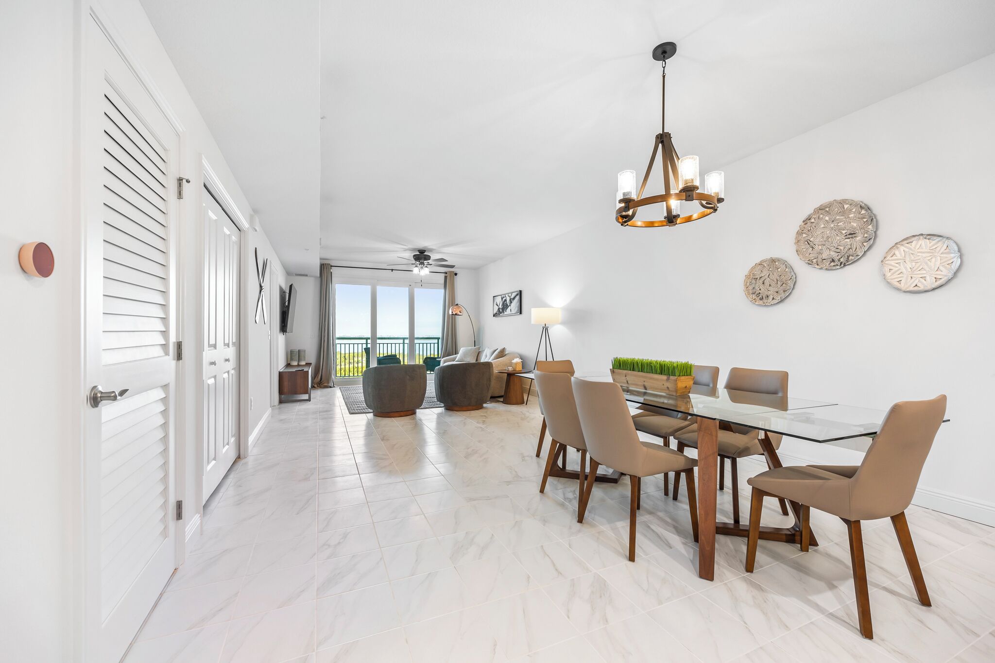 A spacious dining area with a glass table and modern chairs, a ceiling fan, and decorative wall art.