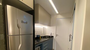 Een compacte keuken met een roestvrijstalen koelkast, een inbouwoven en een spoelbak.