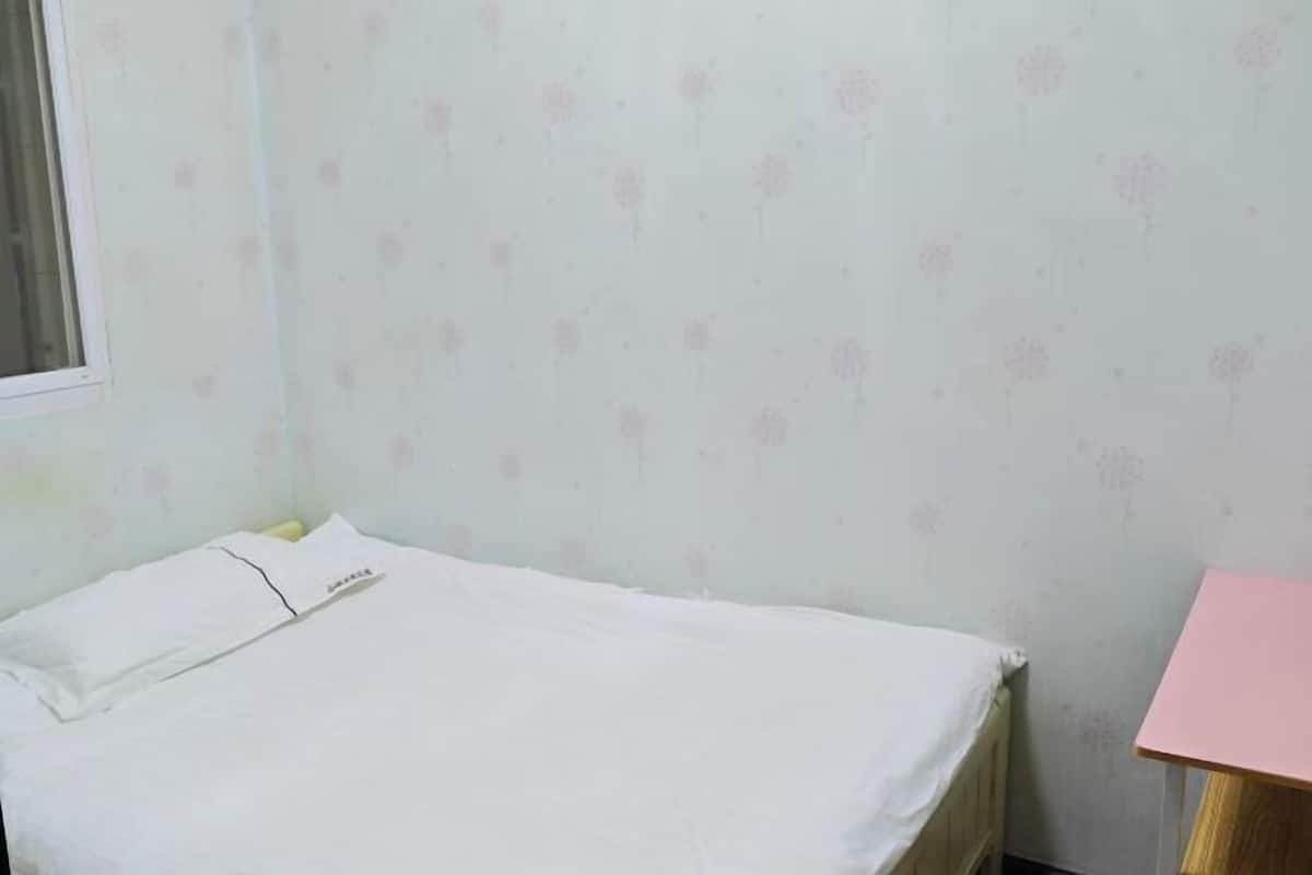A room with a bed, a small table, and a window.
