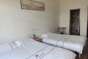 A hotel room with two beds, a small table, a chair, and a painting on the wall. - Xiaocheng Zhijia Hotel (Chengjiang)