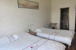 Quarto de hotel com duas camas, uma mesa pequena, uma cadeira e um quadro na parede.