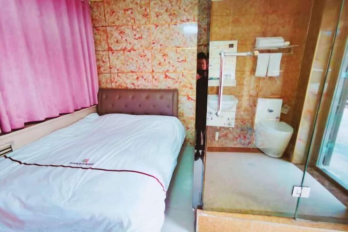 A hotel room with a bed, a shower area, and a window.