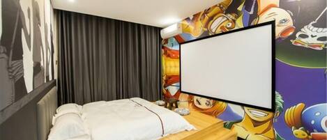 A bedroom with a bed, a large blank screen, and a colorful mural on the wall.