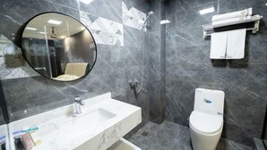 Een badkamer met een marmeren wastafel, toilet, douche en spiegel.