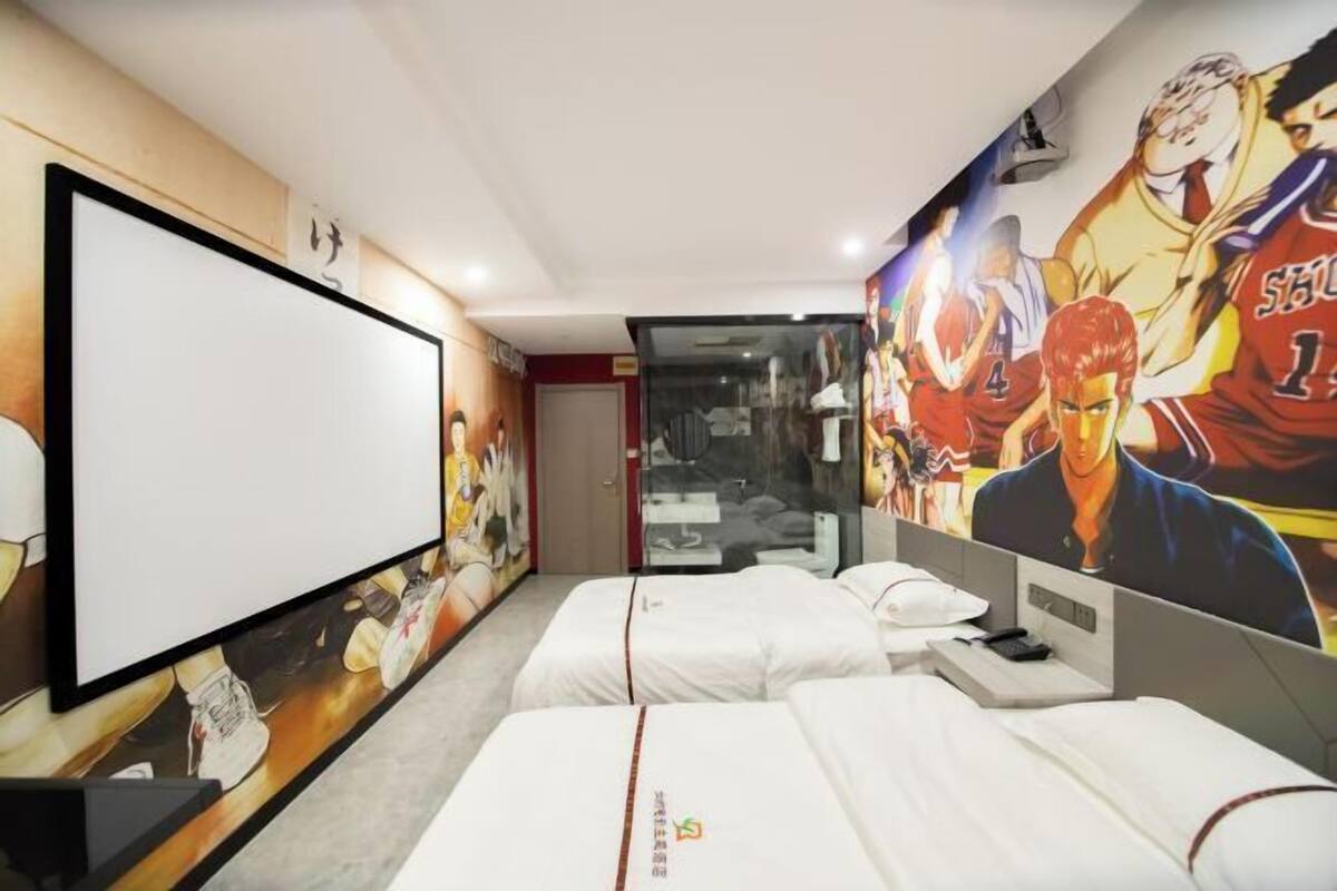 A hotel room with two beds, a large TV, and sports-themed wall art.