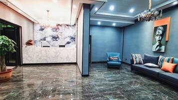A reception area with a marble counter, a sofa with colorful cushions, and a painting on the wall.