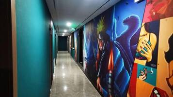 A hallway with a long corridor, walls adorned with colorful murals, and a polished floor.