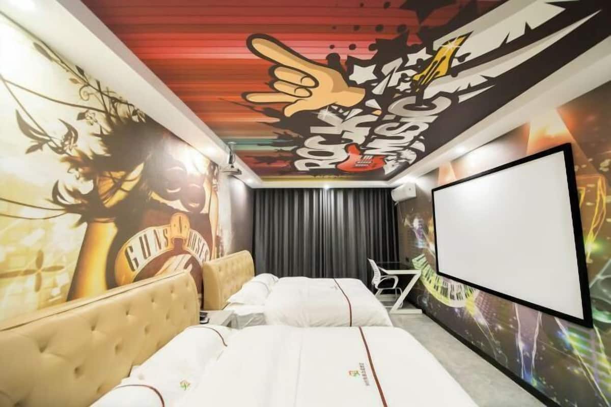 A hotel room with a large bed, a television, and a mural on the wall.