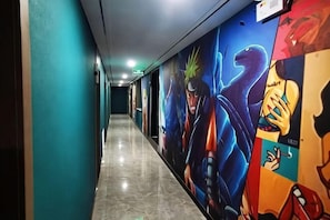 Un pasillo largo con suelo de baldosas y murales coloridos en las paredes.