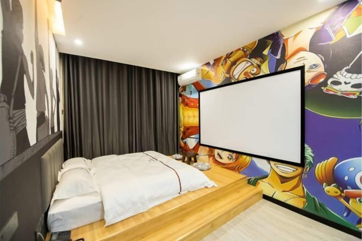 A bedroom with a bed, a TV, and a wall with anime characters.