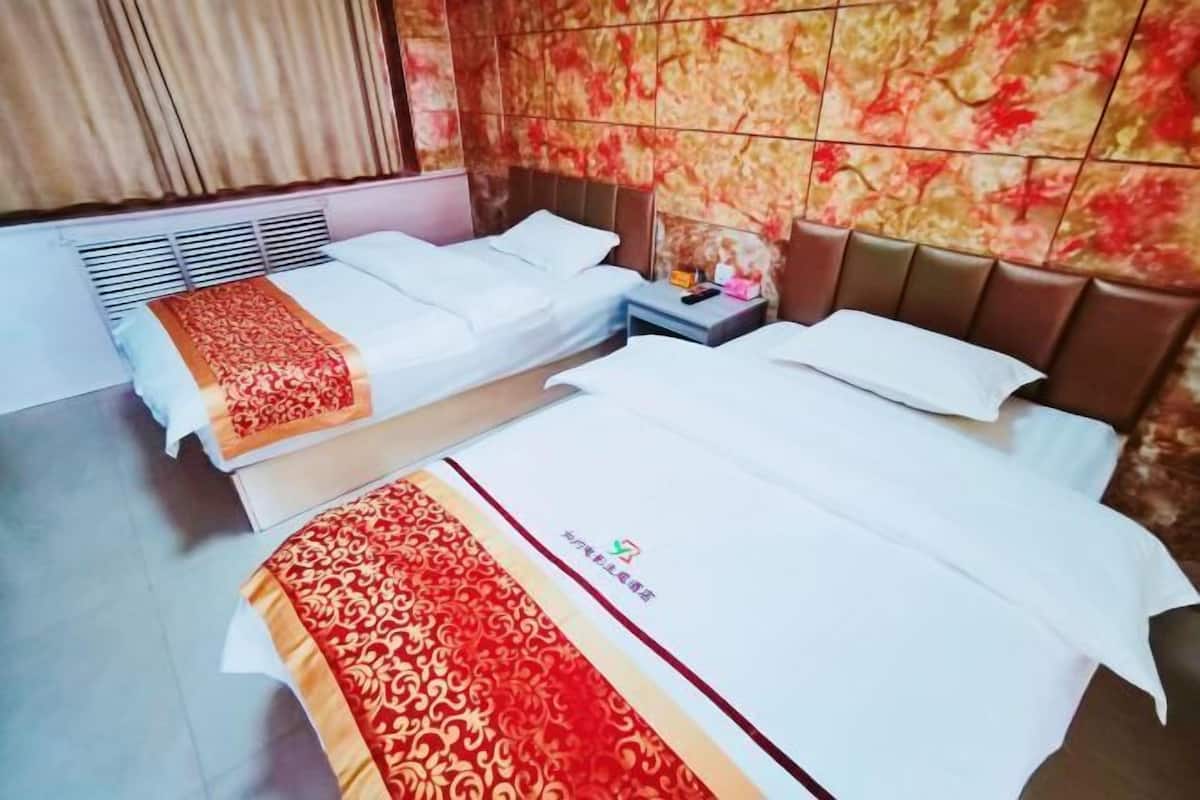 A hotel room with two beds, a nightstand, and a decorative wall.