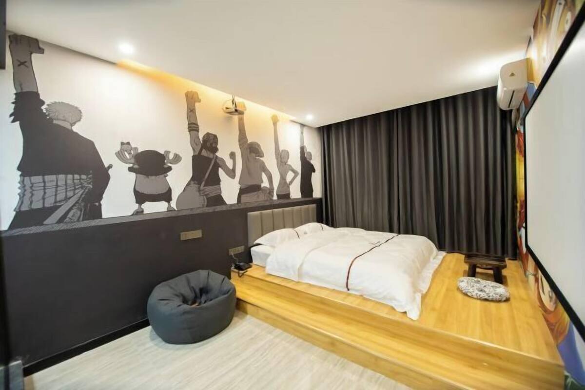 A bedroom with a bed, a bean bag, a wall mural, and a curtain.