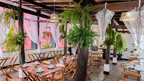 Ein Restaurant mit Holztischen und -stühlen, Blumentöpfen und hängenden Lampen.