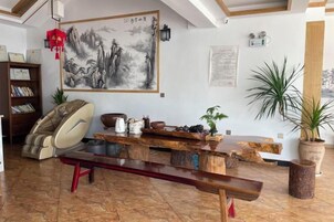A room with a massage chair, a wooden table with decorative items, and a large painting on the wall.