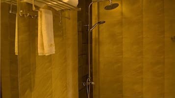 A bathroom with a glass shower enclosure, a towel rack with towels, and a handheld showerhead.