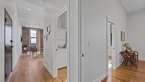 Ein geräumiger Flur mit Holzboden, weißen Wänden und einer Wand in Ziegeloptik. Es gibt einen Essbereich mit Tisch und Stühlen sowie eine Küchenzeile mit Herd und Backofen.