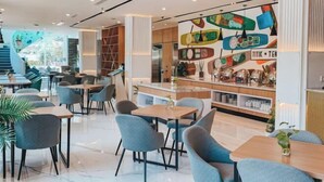 A modern restaurant interior with a central bar area, seating arrangements, and a colorful wall decoration. - Regantris Surabaya (Tegalsari)