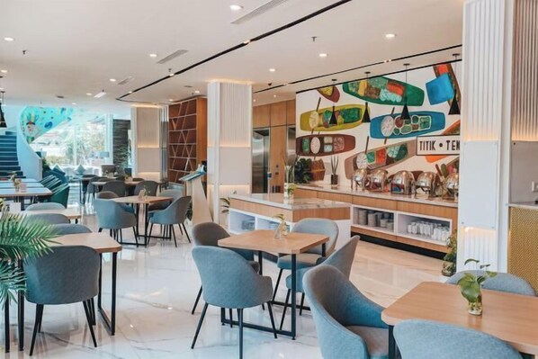A modern restaurant interior with a central bar area, seating arrangements, and a colorful wall decoration. - Regantris Darmo Surabaya (Tegalsari)