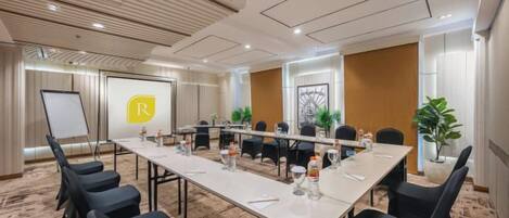 A conference room with a long table, chairs, a whiteboard, and a presentation screen.