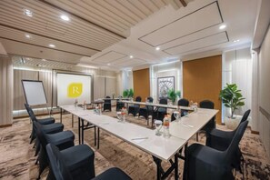 A conference room with a long table, chairs, a whiteboard, and a presentation screen. - Regantris Darmo Surabaya (Tegalsari)