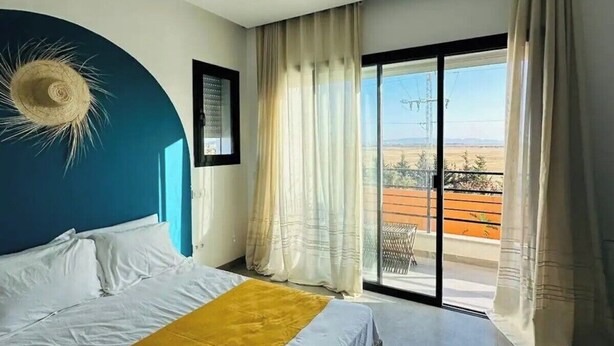 Un dormitorio con una cama grande, vista al exterior a través de un ventanal corredero y un ventilador de techo.