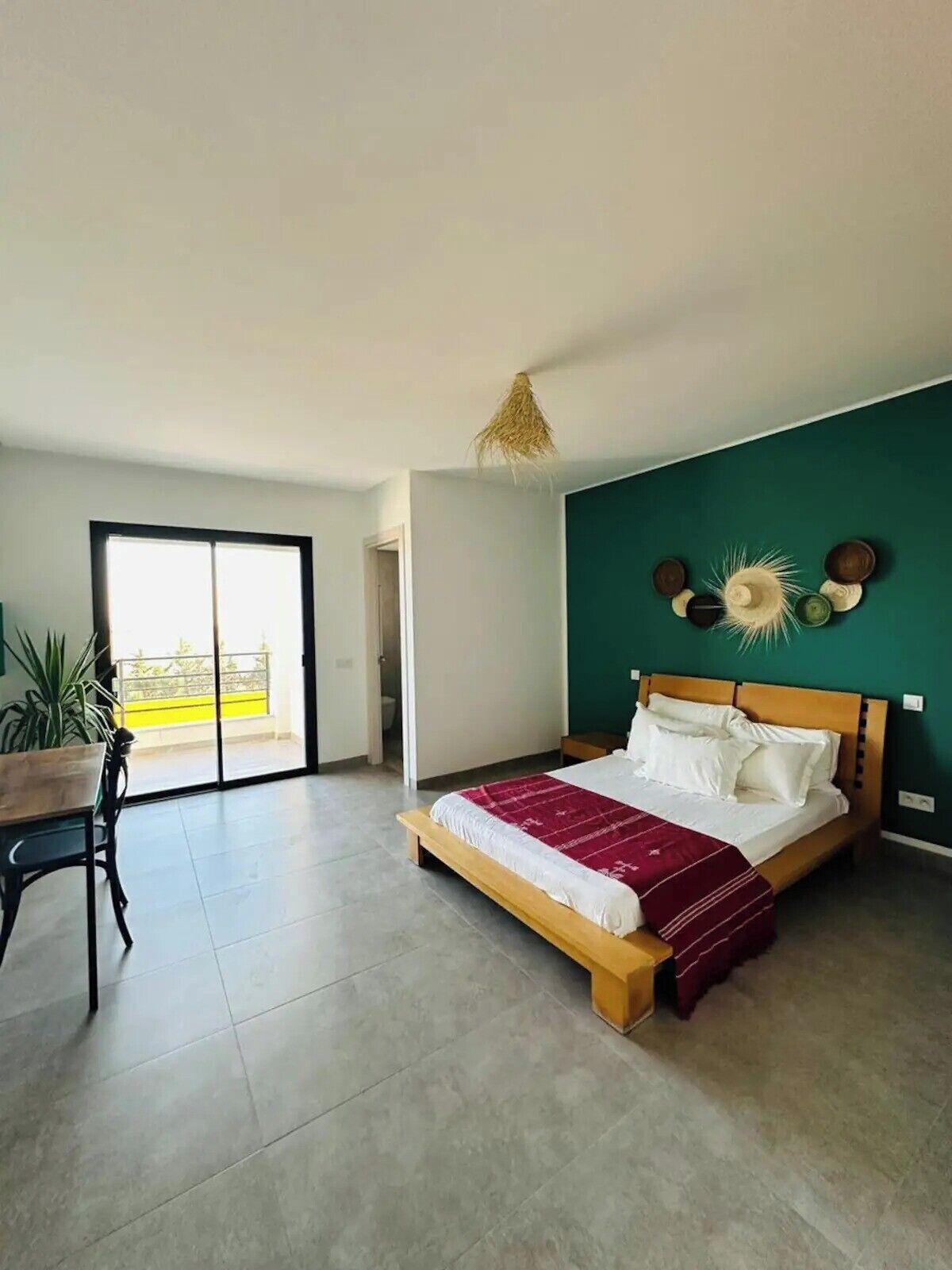 Ein Schlafzimmer mit Bett, Esstisch und Blick ins Freie.