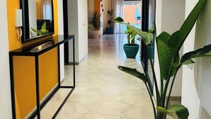 Un pasillo con una pared de acento amarilla, una consola con marco negro y una planta en maceta.