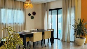 Un comedor moderno con una mesa y sillas, una lámpara colgante y plantas en macetas.
