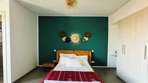 Un dormitorio con una cama de madera, una pared verde de acento y una lámpara de techo.