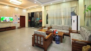 A hotel lobby with a reception desk, sofas, a television, and a refrigerator. - Starry Inn (Renhua)