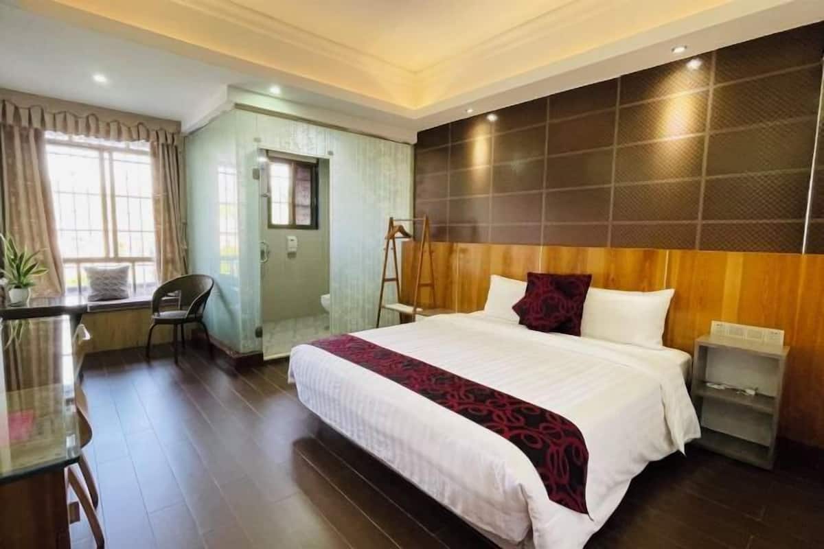 A hotel room with a large bed, bedside tables, a desk, and a chair.