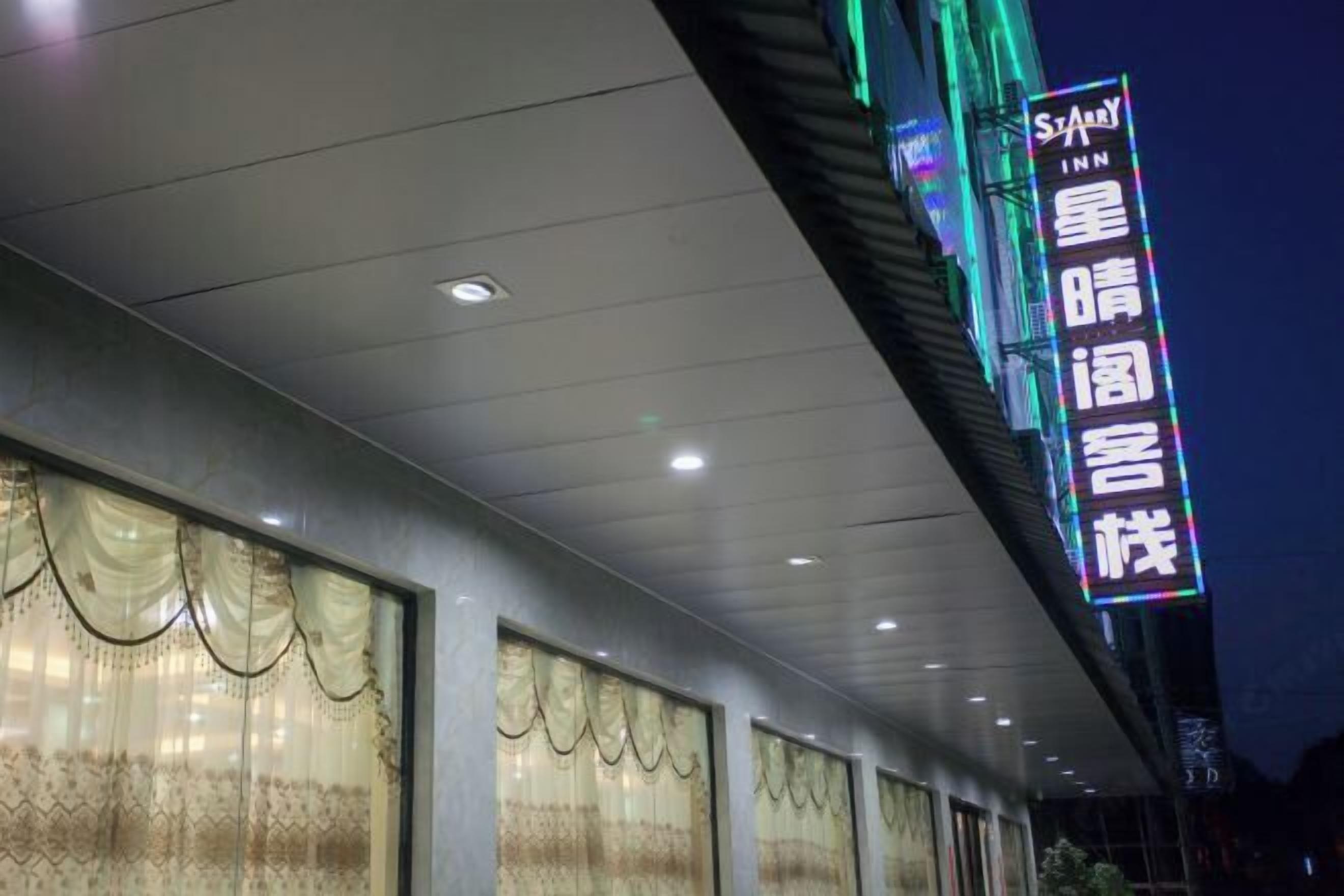 A hotel exterior with a neon sign in a foreign language, large windows, and a modern architectural design.