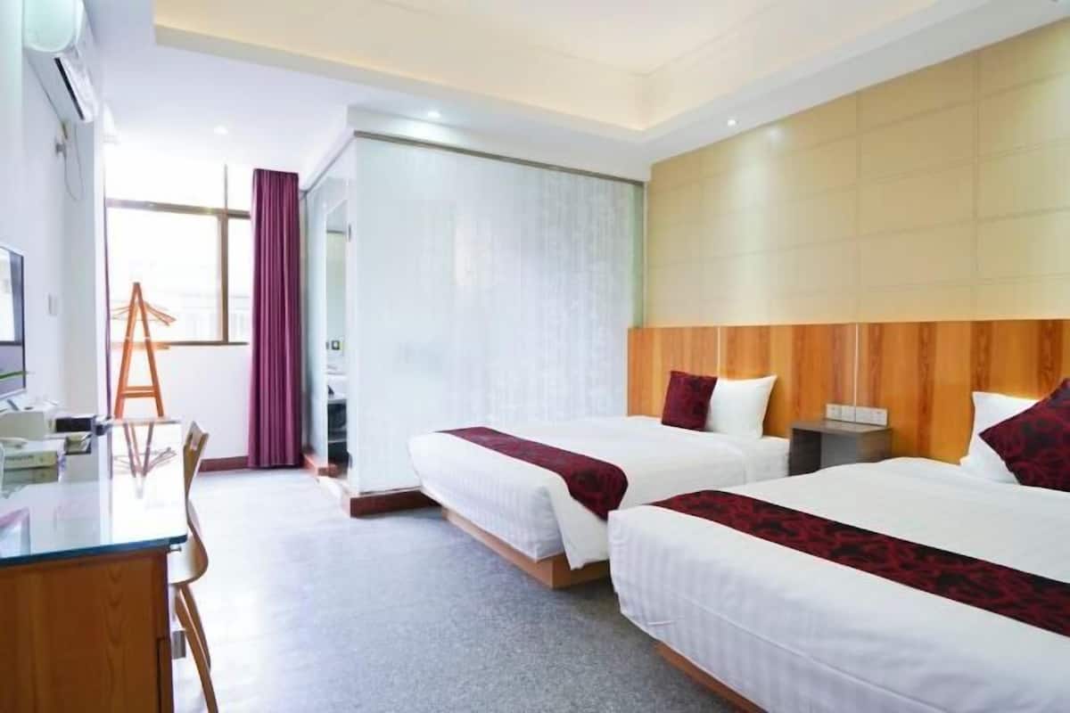 A hotel room with two beds, a desk, and a chair.