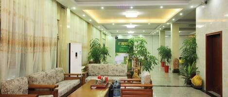 A lobby with sofas, a coffee table, and potted plants.