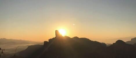 A mountain landscape with the sun setting behind the peaks.