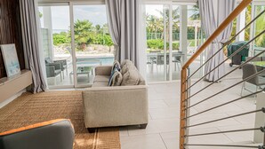 Ein großzügiger Wohnbereich mit einer Couch, einem Couchtisch und Blick auf einen Pool und eine Sitzgelegenheit im Freien.