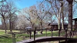 A wooden bridge in a park with a gazebo and picnic tables in the background. - Knots Landing - A romantic getaway w/ hot tub (Afton)