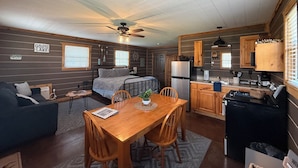 A compact RV interior with a kitchenette, a dining area, a bed, and a small living space. - Knots Landing - A romantic getaway w/ hot tub (Afton)