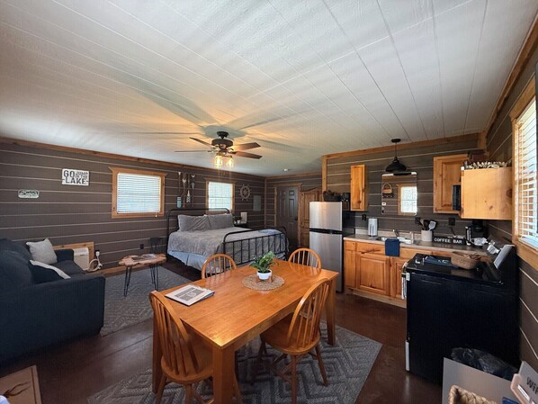 Interior compacto de autocaravana con kitchenette, comedor, cama y pequeño espacio habitable.