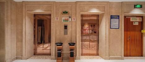 A hotel lobby with a reception desk, a staircase, and an elevator.