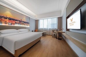 Une chambre d’hôtel avec un grand lit, un bureau, une chaise et un téléviseur fixé au mur.