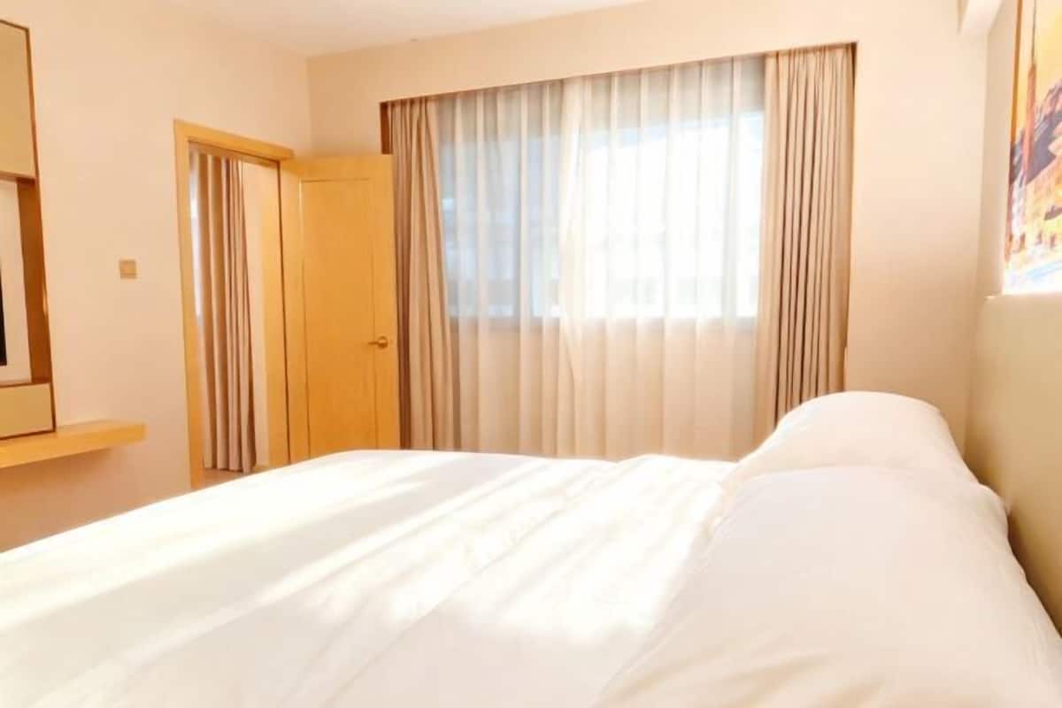Hotellihuone, jossa on sänky, ovi ja ikkuna, jossa on verhot.