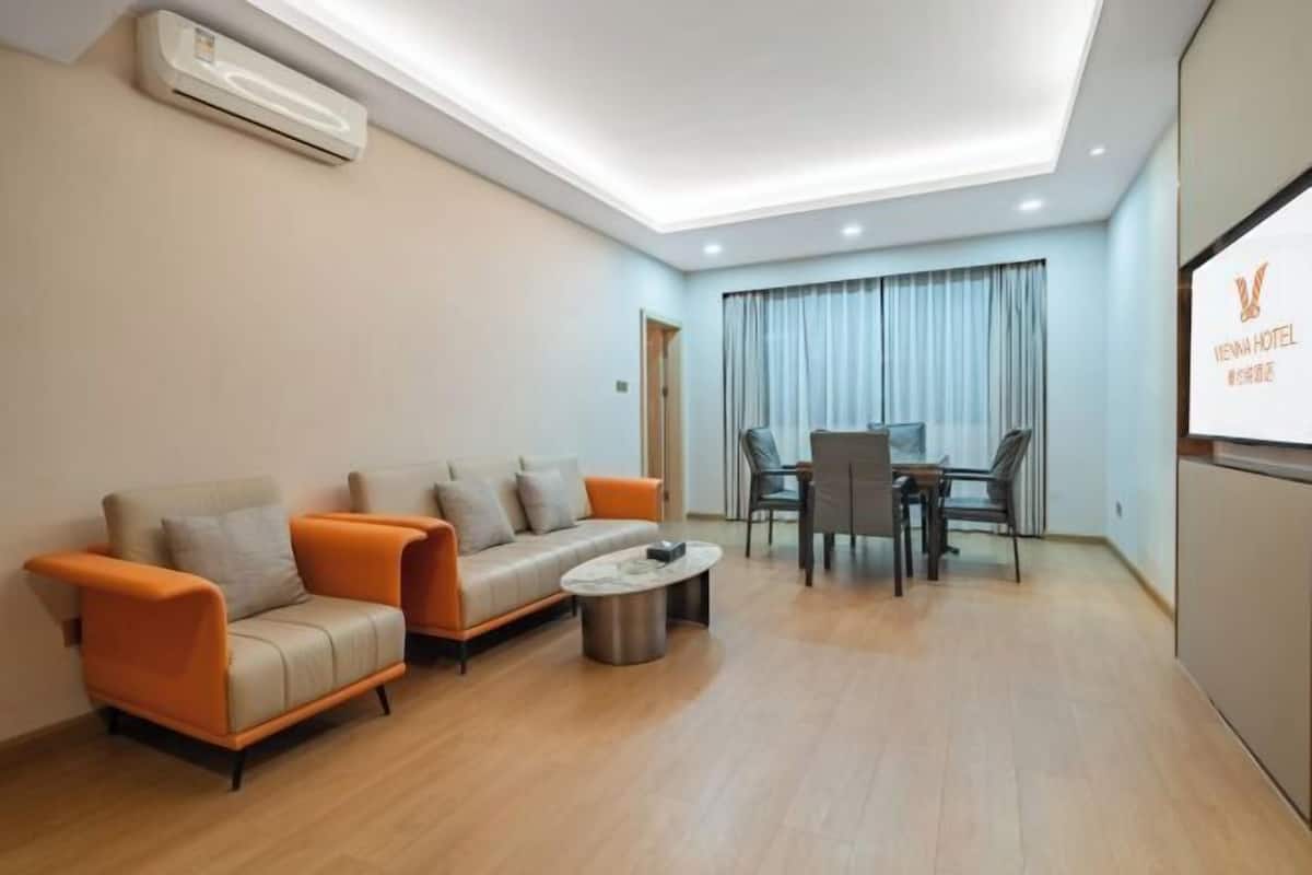Una habitación de hotel moderna con un conjunto de sofás, una mesa de comedor con sillas y una pequeña mesa de centro.
