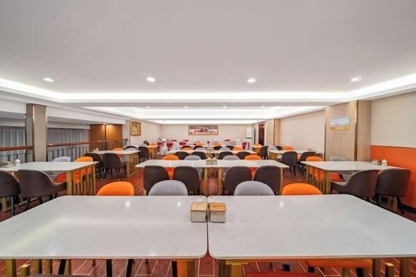 Une salle de conférence dotée de plusieurs tables et de nombreuses chaises, disposées en rangées.
